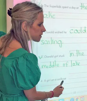 A woman in green shirt writing on white board.