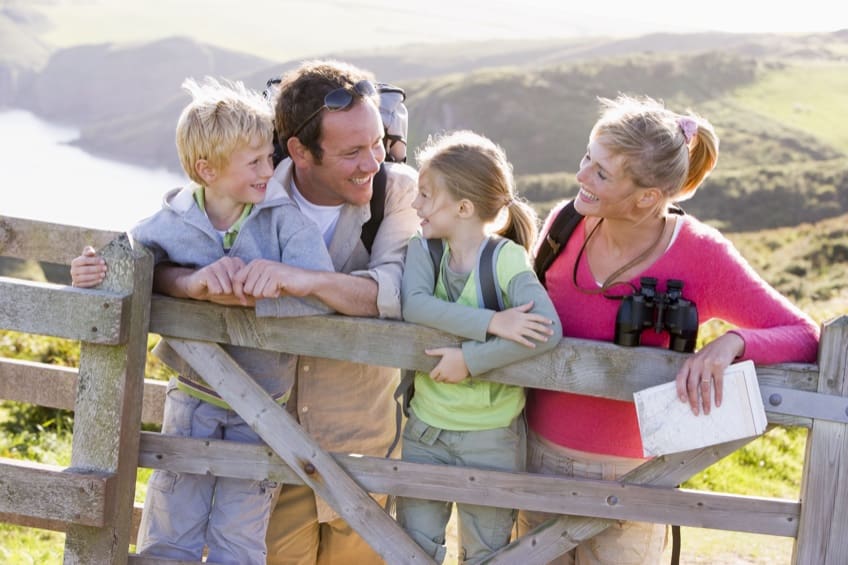 A family of four standing behind a wooden fence.