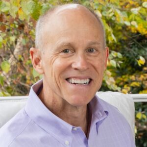 Smiling man, outdoors, purple shirt.