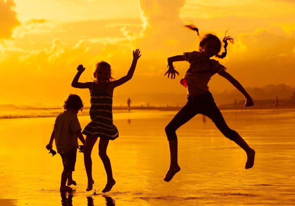 A group of people jumping in the air on top of a beach.